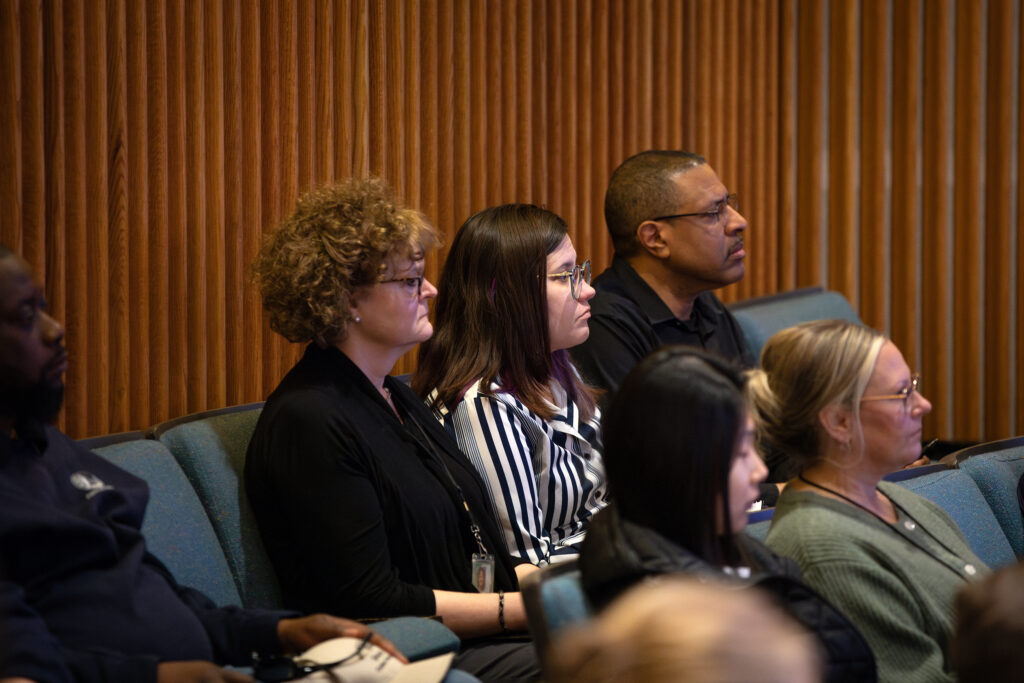 Close up of the profile view of three employees sitting side-by-side watching with stoic faces