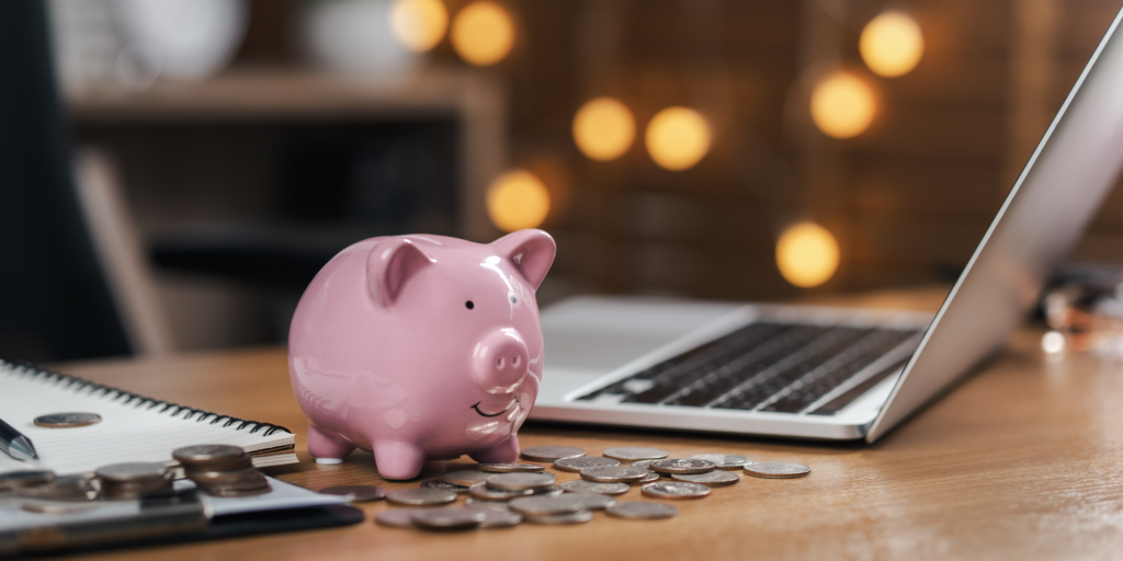 piggy bank on a desk next to a laptop computer